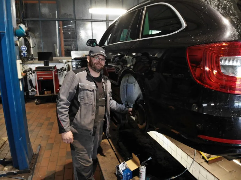 Kfz-Mechaniker des Autohaus Houtrouw bei der Reparatur eines Fahrzeugs auf der Hebebühne
